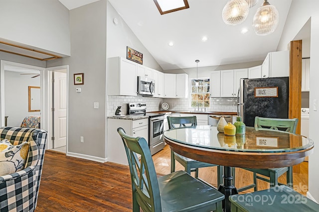 kitchen with pendant lighting, appliances with stainless steel finishes, wood finished floors, and white cabinets