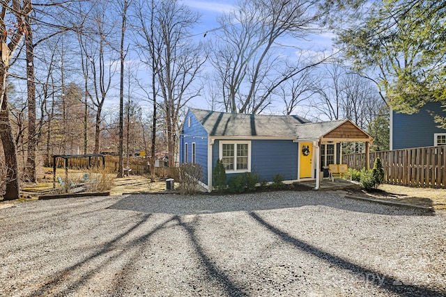 view of front facade featuring a shingled roof and fence