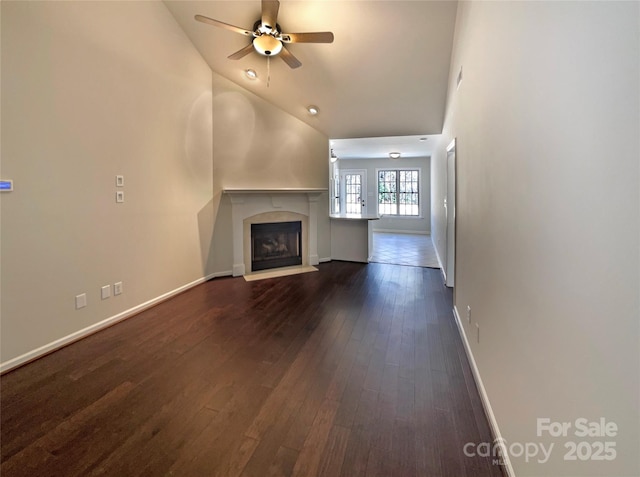 unfurnished living room featuring baseboards, dark wood-style floors, a fireplace with flush hearth, ceiling fan, and high vaulted ceiling