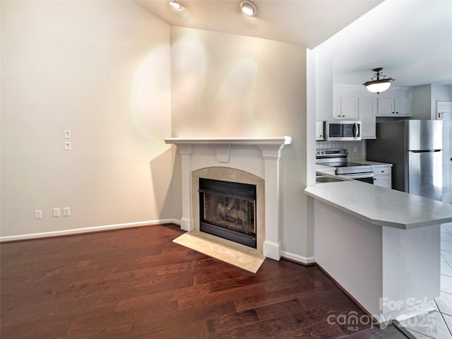 unfurnished living room featuring a premium fireplace, baseboards, and wood finished floors