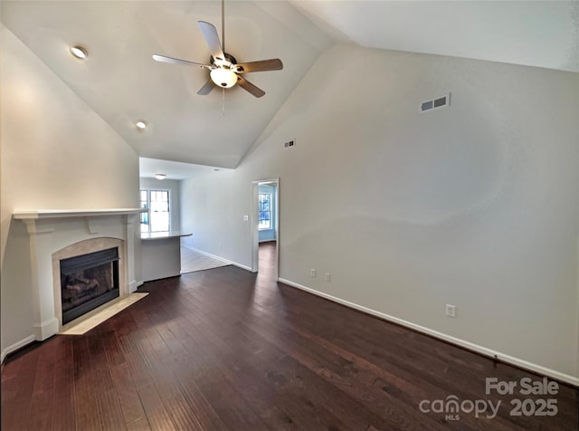 unfurnished living room with high vaulted ceiling, a fireplace with flush hearth, visible vents, baseboards, and dark wood finished floors