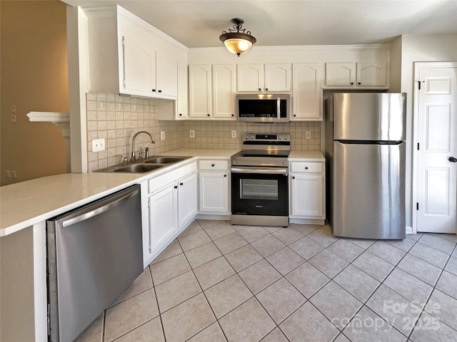 kitchen with light tile patterned floors, appliances with stainless steel finishes, decorative backsplash, and a sink