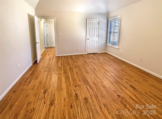 unfurnished bedroom featuring baseboards, vaulted ceiling, and wood finished floors