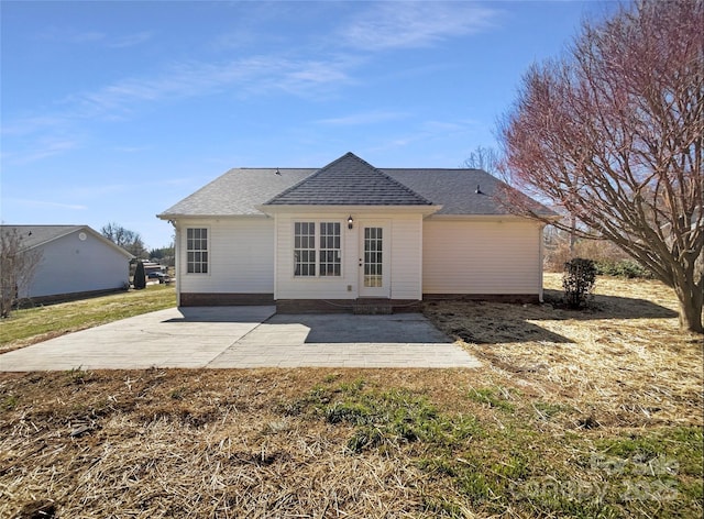 rear view of house featuring a patio area and a shingled roof