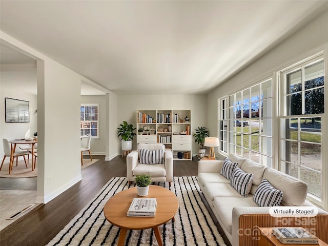 living room featuring a healthy amount of sunlight, baseboards, and wood finished floors