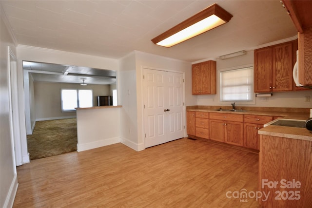 kitchen featuring light wood-style flooring, baseboards, light countertops, and a sink