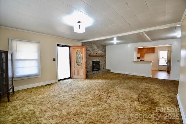 unfurnished living room with ornamental molding, a brick fireplace, carpet flooring, and baseboards