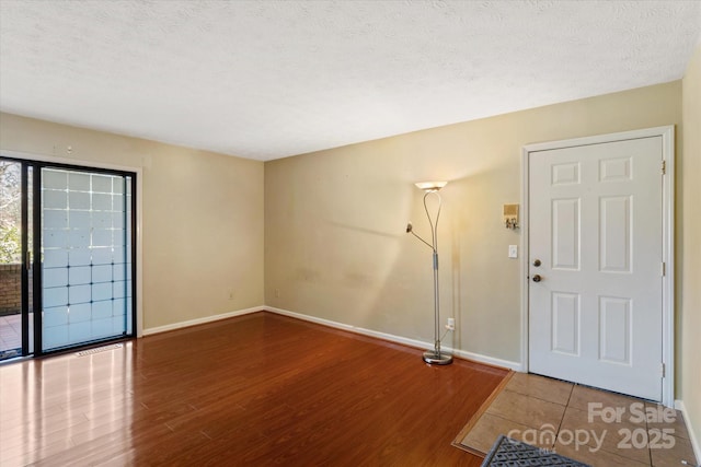 foyer with a textured ceiling, wood finished floors, and baseboards