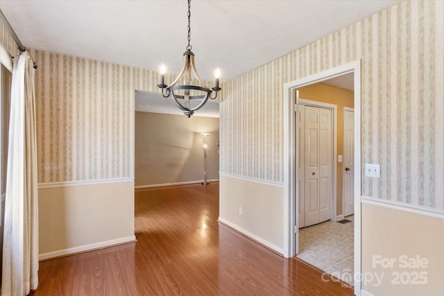 unfurnished room with wood finished floors, baseboards, and wallpapered walls