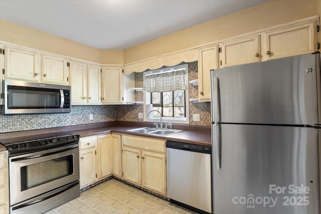 kitchen with stainless steel appliances, dark countertops, a sink, and tasteful backsplash