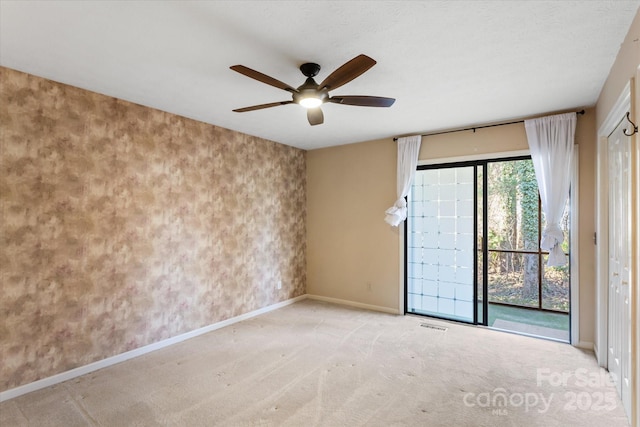 carpeted empty room with ceiling fan and baseboards