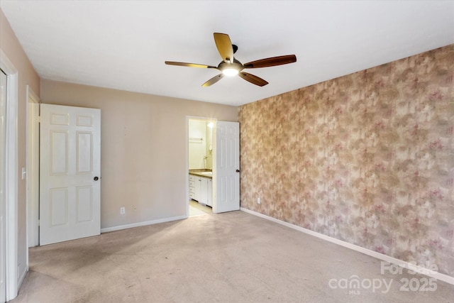 unfurnished bedroom with carpet floors, ensuite bath, baseboards, and ceiling fan