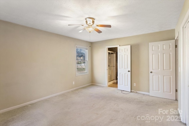 unfurnished bedroom featuring light carpet, ceiling fan, baseboards, and a textured ceiling