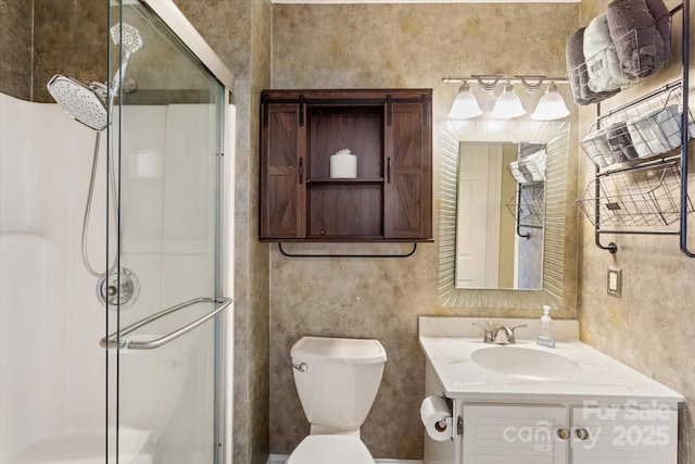 bathroom with toilet, a shower stall, and vanity