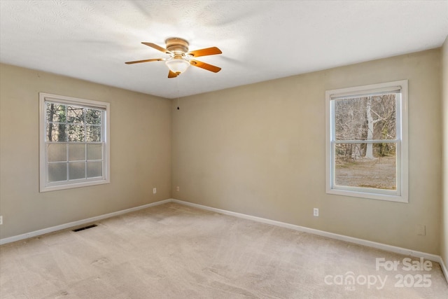 spare room featuring a ceiling fan, visible vents, light carpet, and baseboards