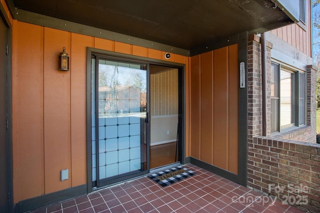 entrance to property featuring board and batten siding and brick siding