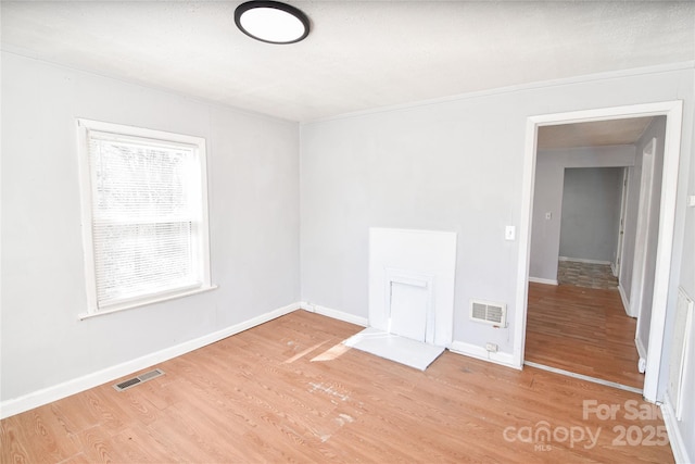 spare room with wood finished floors, visible vents, and baseboards