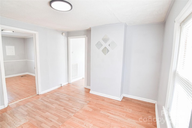 empty room featuring light wood-style flooring, visible vents, and baseboards