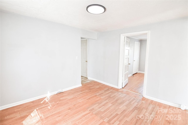 spare room featuring light wood-type flooring and baseboards