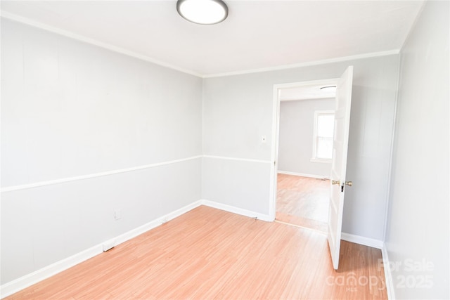 unfurnished room with ornamental molding, light wood-style flooring, and baseboards