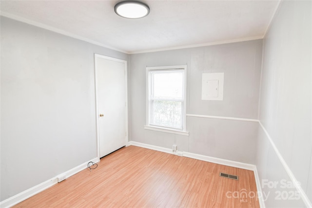 unfurnished room featuring ornamental molding, wood finished floors, visible vents, and baseboards