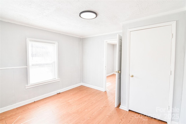 unfurnished room with light wood-style flooring, baseboards, and a textured ceiling