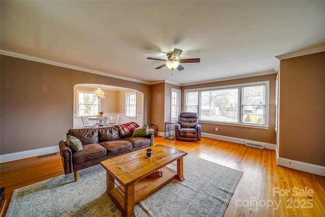 living room with arched walkways, light wood-style flooring, ornamental molding, and visible vents