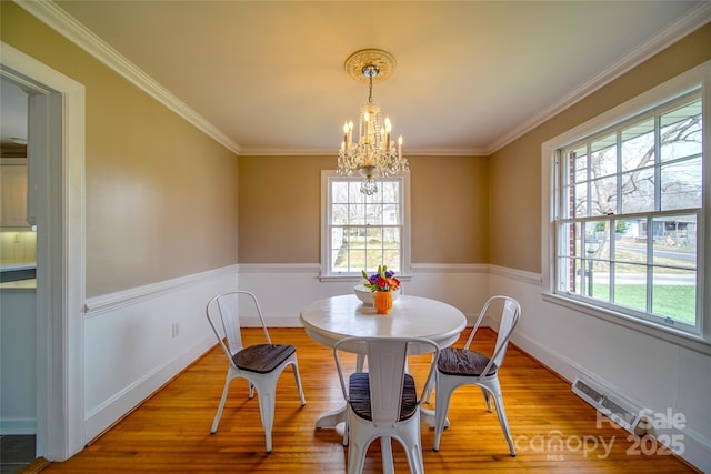 dining area featuring wood finished floors, visible vents, baseboards, an inviting chandelier, and crown molding