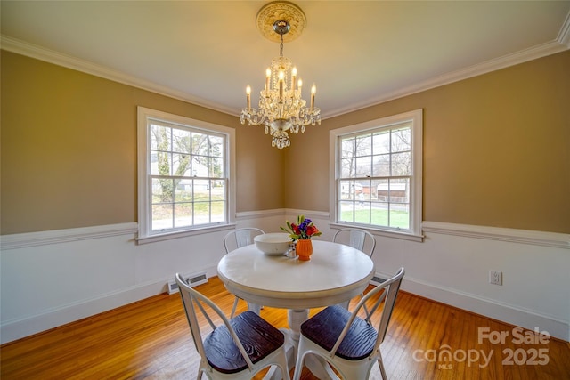 dining room featuring ornamental molding, visible vents, a notable chandelier, and wood finished floors