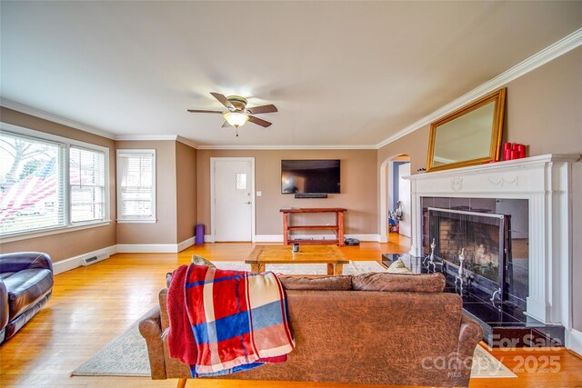 living room featuring wood finished floors, a tile fireplace, visible vents, and crown molding