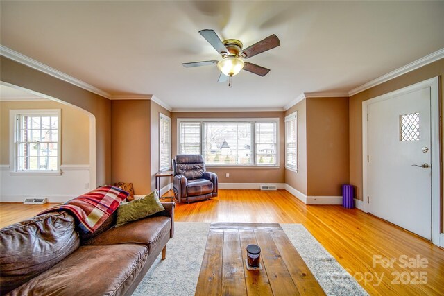 unfurnished living room with a healthy amount of sunlight, light wood finished floors, baseboards, and crown molding