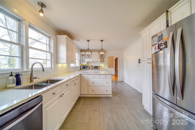 kitchen featuring arched walkways, stainless steel appliances, a sink, white cabinets, and light countertops