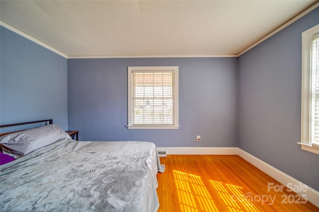 bedroom with baseboards, visible vents, ornamental molding, wood finished floors, and a textured ceiling