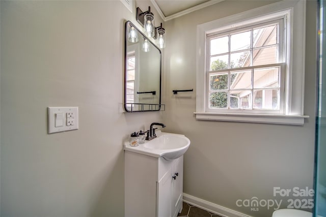 bathroom featuring toilet, ornamental molding, vanity, and baseboards