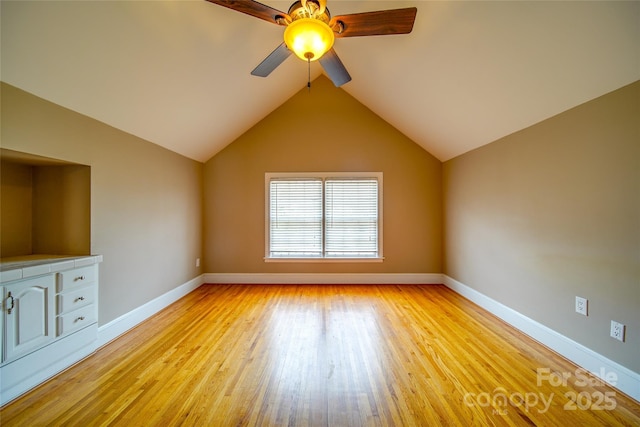 unfurnished living room featuring light wood-style floors, lofted ceiling, baseboards, and a ceiling fan