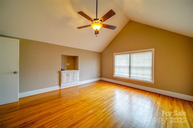 empty room featuring light wood-type flooring, ceiling fan, lofted ceiling, and baseboards