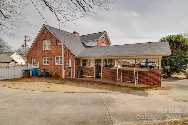 exterior space featuring brick siding, a chimney, covered porch, central AC unit, and fence