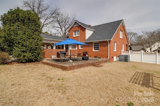 back of house featuring brick siding, a shingled roof, a patio area, fence, and central AC