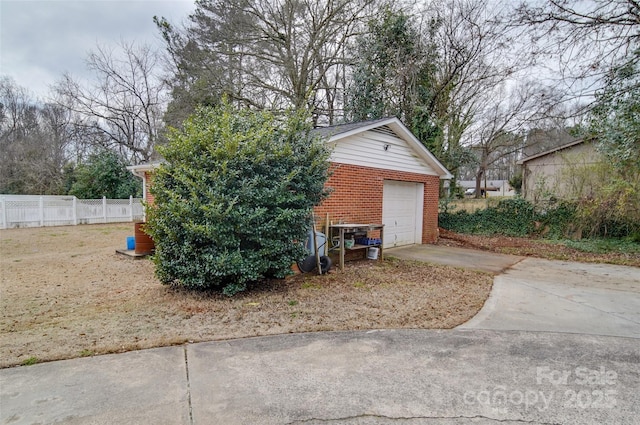 garage with concrete driveway and fence