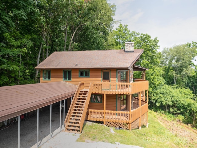 view of front of property with a chimney, a shingled roof, a front yard, a deck, and stairs