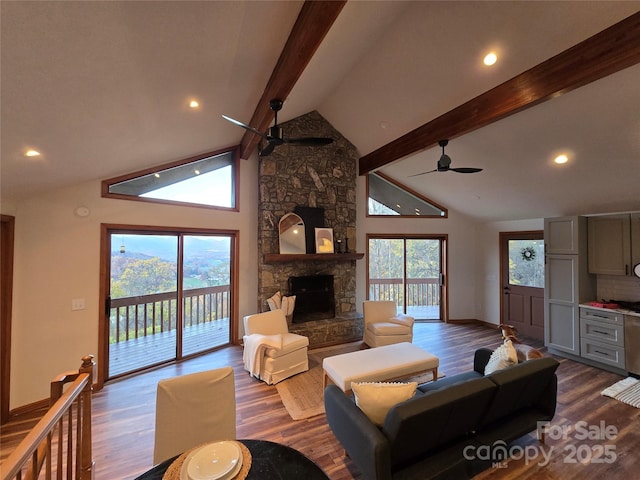 living area featuring a wealth of natural light, beamed ceiling, a fireplace, and a ceiling fan