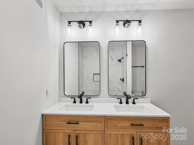 bathroom with double vanity, walk in shower, and a sink