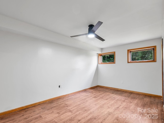 spare room featuring light wood finished floors, baseboards, and a ceiling fan