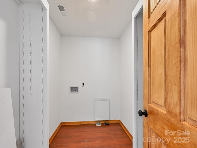 washroom featuring laundry area, baseboards, visible vents, and wood finished floors