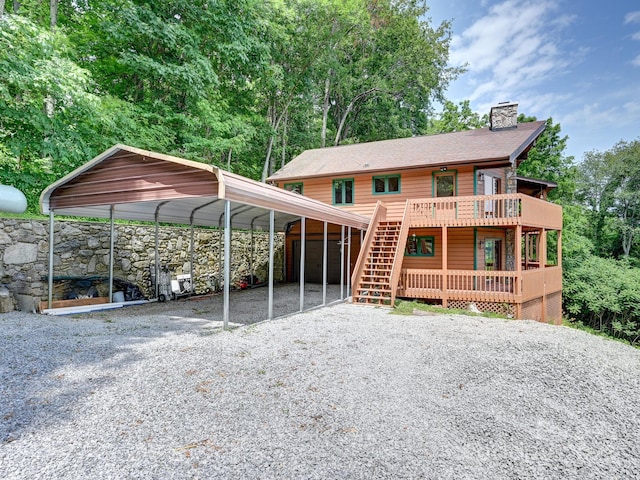 rustic home with a carport, gravel driveway, a chimney, and a deck