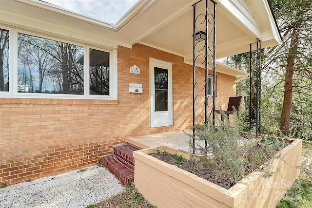 property entrance featuring a patio and brick siding