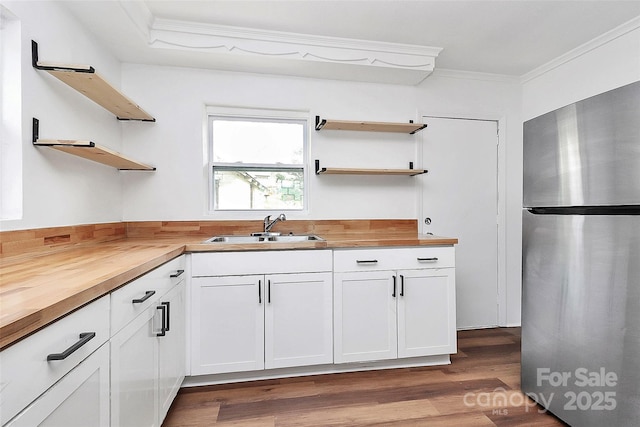 kitchen featuring wood counters, ornamental molding, freestanding refrigerator, open shelves, and a sink