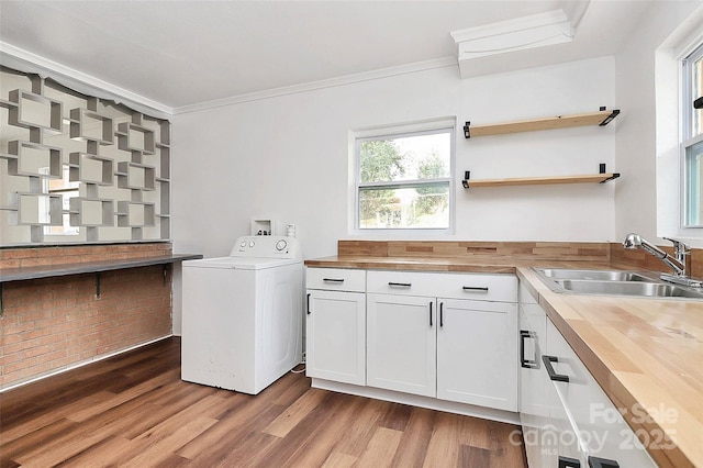 washroom with dark wood-style flooring, crown molding, cabinet space, a sink, and washer / dryer