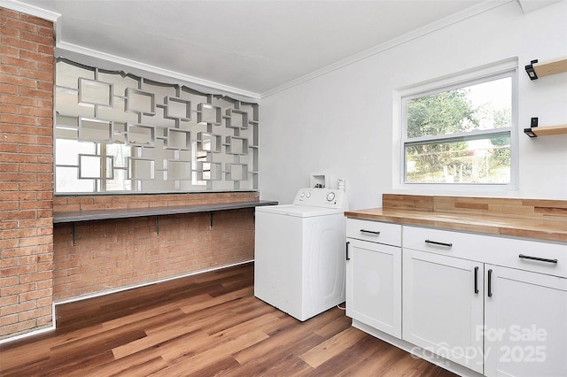 laundry room with cabinet space, washer / dryer, brick wall, wood finished floors, and crown molding