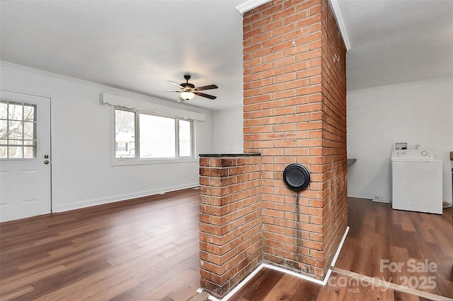 unfurnished living room with ceiling fan, dark wood-type flooring, baseboards, ornamental molding, and washer / dryer